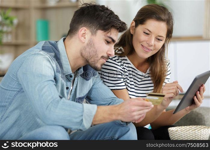 couple shopping online with tablet and credit card at home