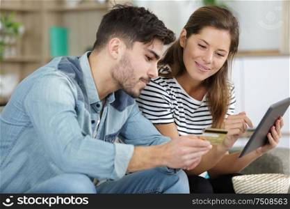 couple shopping online with tablet and credit card at home