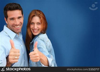 Couple showing thumbs up on blue background