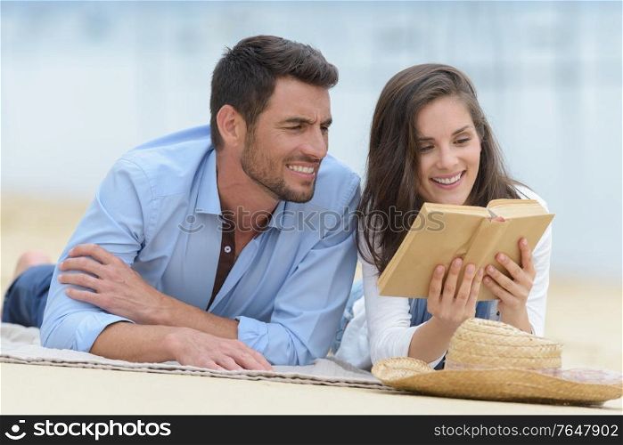 couple sitting and reading on terrace near the water