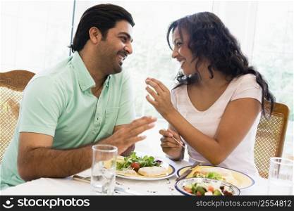 Couple sitting at dinner table smiling (high key)