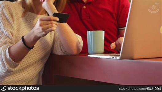Couple sitting at table making online purchase using credit card