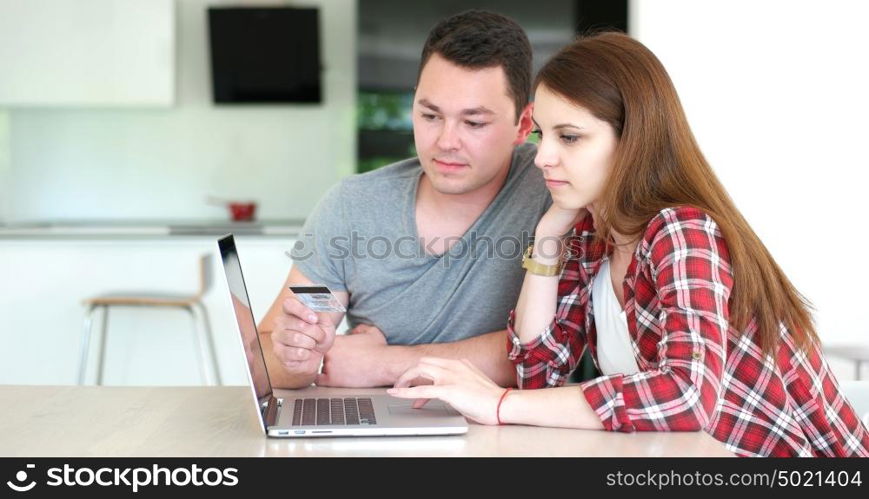 Couple sitting at table making online purchase using credit card