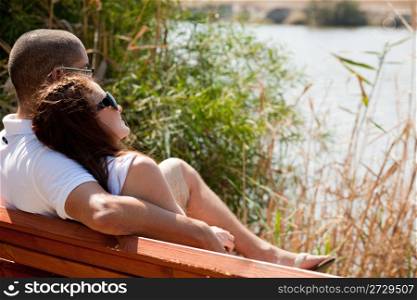 Couple sitting at the wooden bench lake view