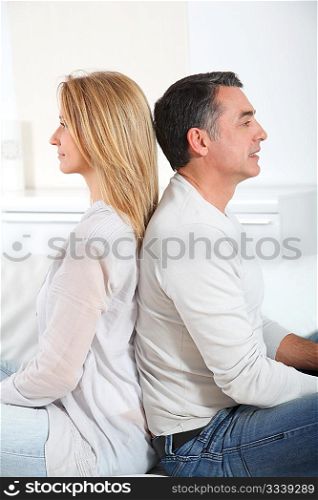 Couple sitting back to back on sofa