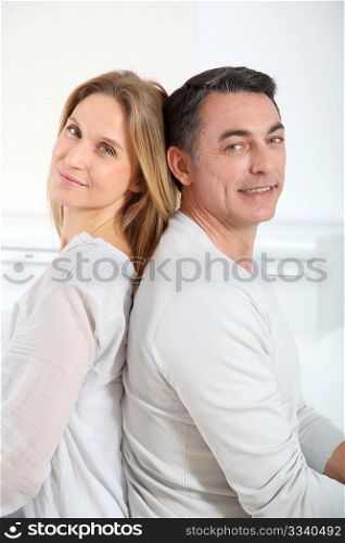 Couple sitting back to back on sofa