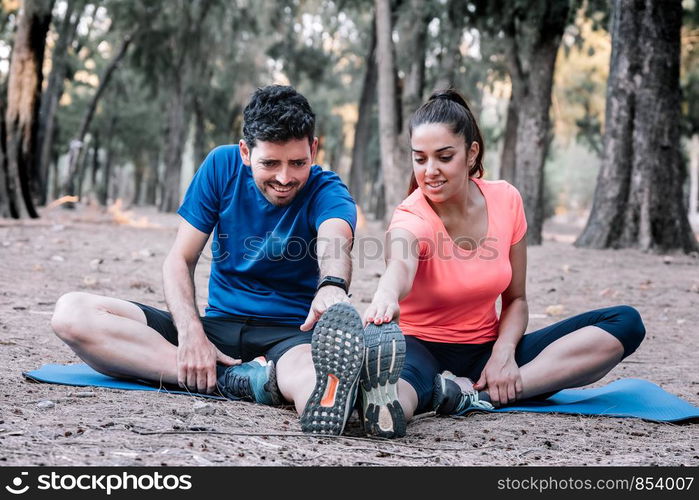 couple sitting in a park doing stretching exercises