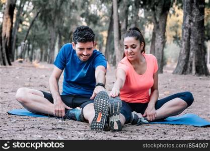 couple sitting in a park doing stretching exercises