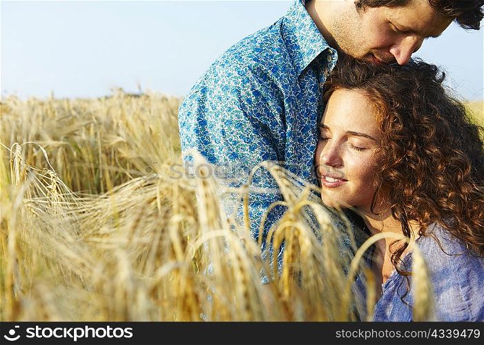 Couple sitting in a wheat field, smiling