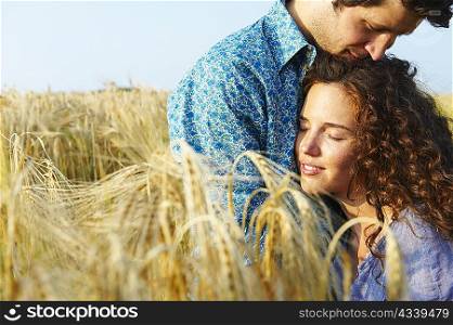 Couple sitting in a wheat field, smiling