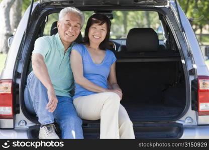 Couple sitting in back of van smiling