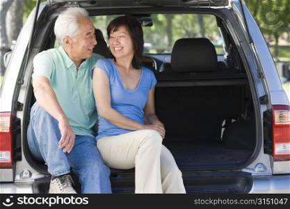 Couple sitting in back of van smiling