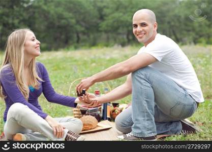 Couple sitting in blanket smiling with picnic mode on green grass