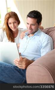 Couple sitting in couch with laptop computer