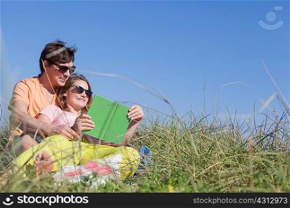 Couple sitting in grass reading book