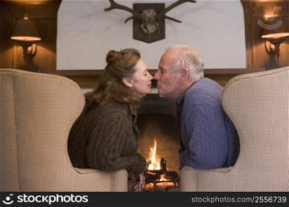 Couple sitting in living room by fireplace kissing