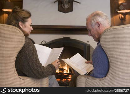 Couple sitting in living room by fireplace reading