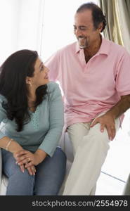 Couple sitting in living room smiling (high key)