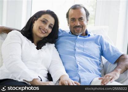Couple sitting in living room smiling (high key)