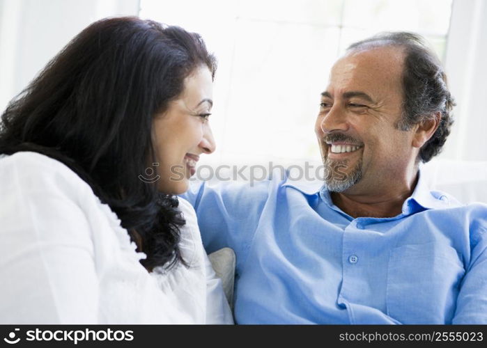 Couple sitting in living room smiling (high key)