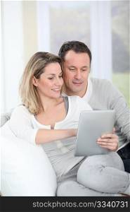 Couple sitting in sofa with electronic tab