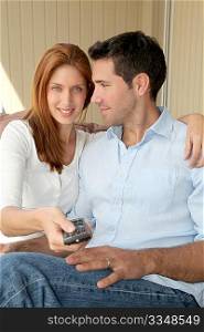 Couple sitting in sofa with tv remote control