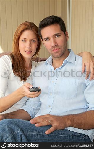 Couple sitting in sofa with tv remote control