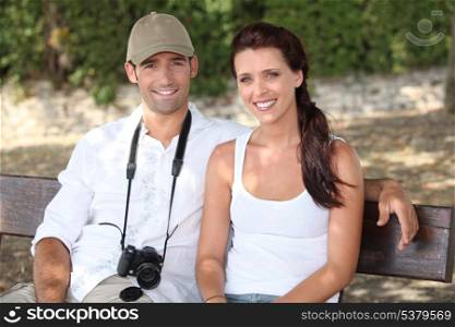 Couple sitting on a bench with a camera