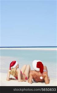 Couple Sitting On Beach Wearing Santa Hats