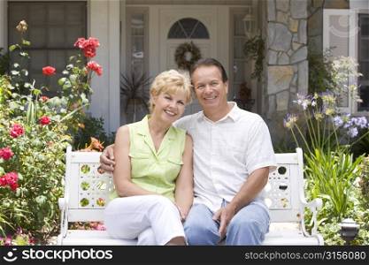 Couple Sitting On Bench Outside House