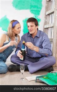 Couple sitting on floor and having champagne at their new apartment