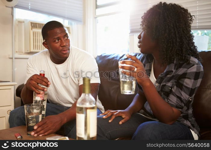 Couple Sitting On Sofa Drinking Alcohol And Arguing