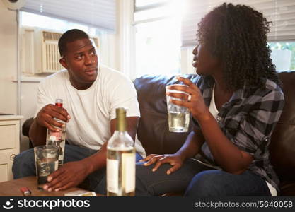 Couple Sitting On Sofa Drinking Alcohol And Arguing