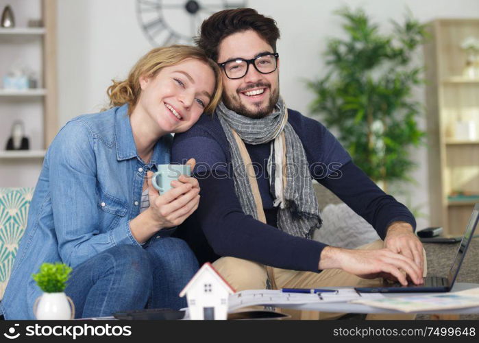 couple sitting on sofa drinking coffe or tea using laptop