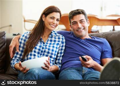 Couple Sitting On Sofa Watching TV Together