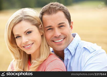 Couple Sitting On Straw Bales In Harvested Field