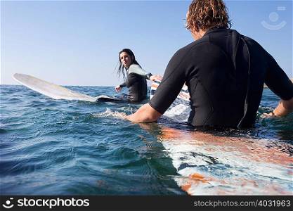Couple sitting on surfboards