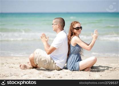 Couple sitting on the beach sand and doing exercises