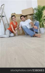 Couple sitting on the floor with moving cardboards