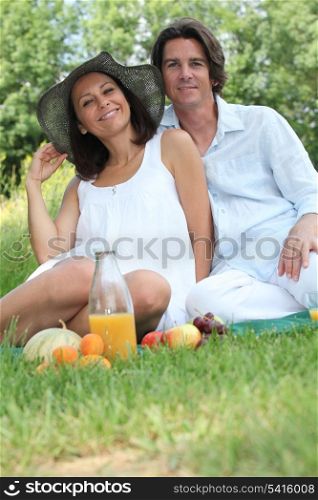 Couple sitting on the grass eating fruit
