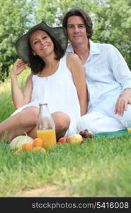 Couple sitting on the grass eating fruit