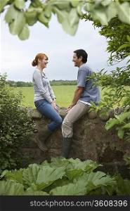Couple sitting on wall in countryside
