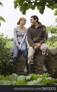 Couple sitting on wall in countryside