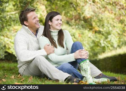 Couple sitting outdoors smiling (selective focus)