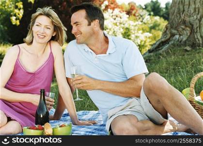Couple sitting outdoors with picnic smiling