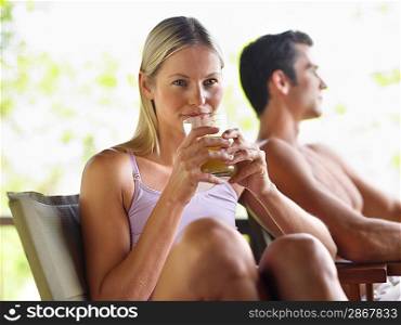 Couple sitting outdoors woman drinking juice focus on foreground