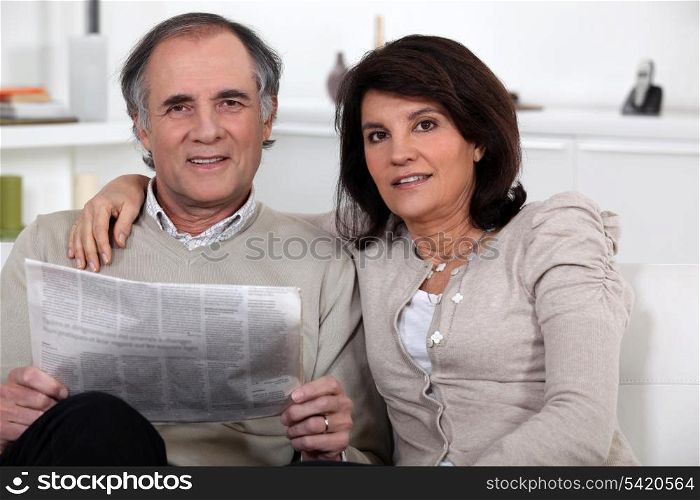 Couple sitting reading a newspaper