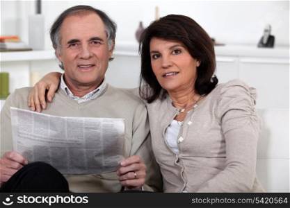 Couple sitting reading a newspaper