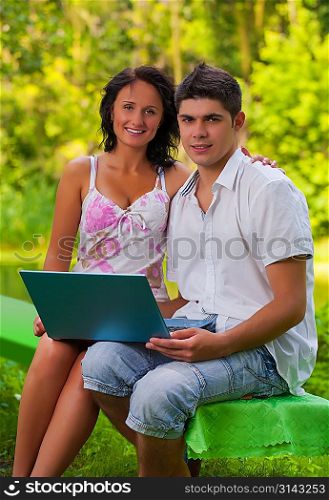 couple sitting with laptop in park
