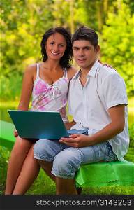 couple sitting with laptop in park